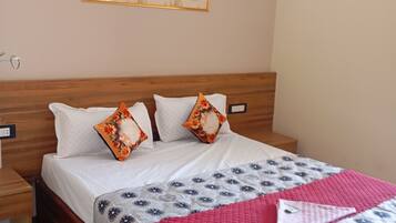Una cama bien hecha con almohadillas florales, colcha roja y cubrecama estampado.