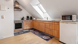 Une cuisine dotée d’une lucarne, de meubles en bois, d’un réfrigérateur et d’un four à micro-ondes.