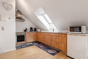 Una cocina con tragaluz, armarios de madera, un refrigerador y un microondas.