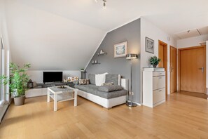 Uma sala de estar moderna com sofá, TV e uma mesinha.
