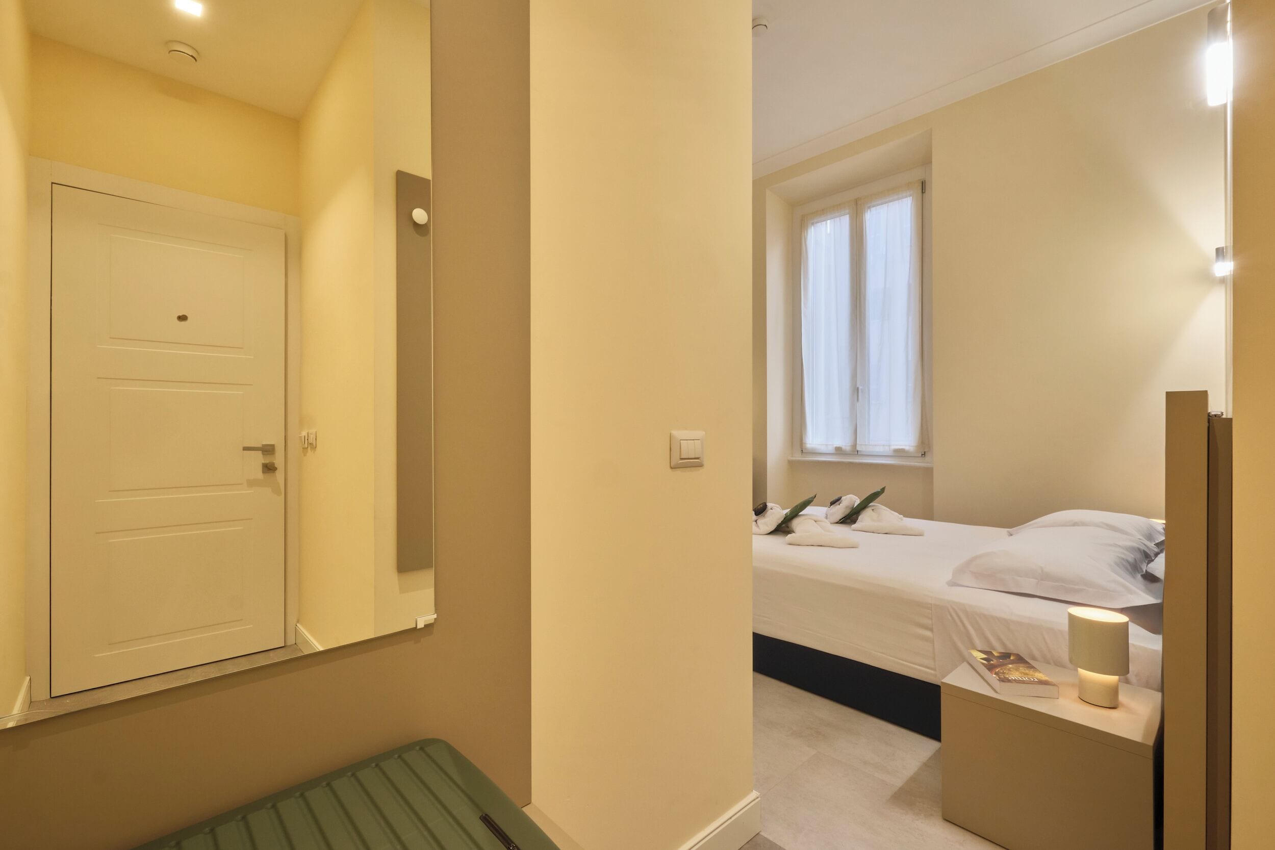 A bedroom with a bed, bedside table, lamp, and a window with curtains.
