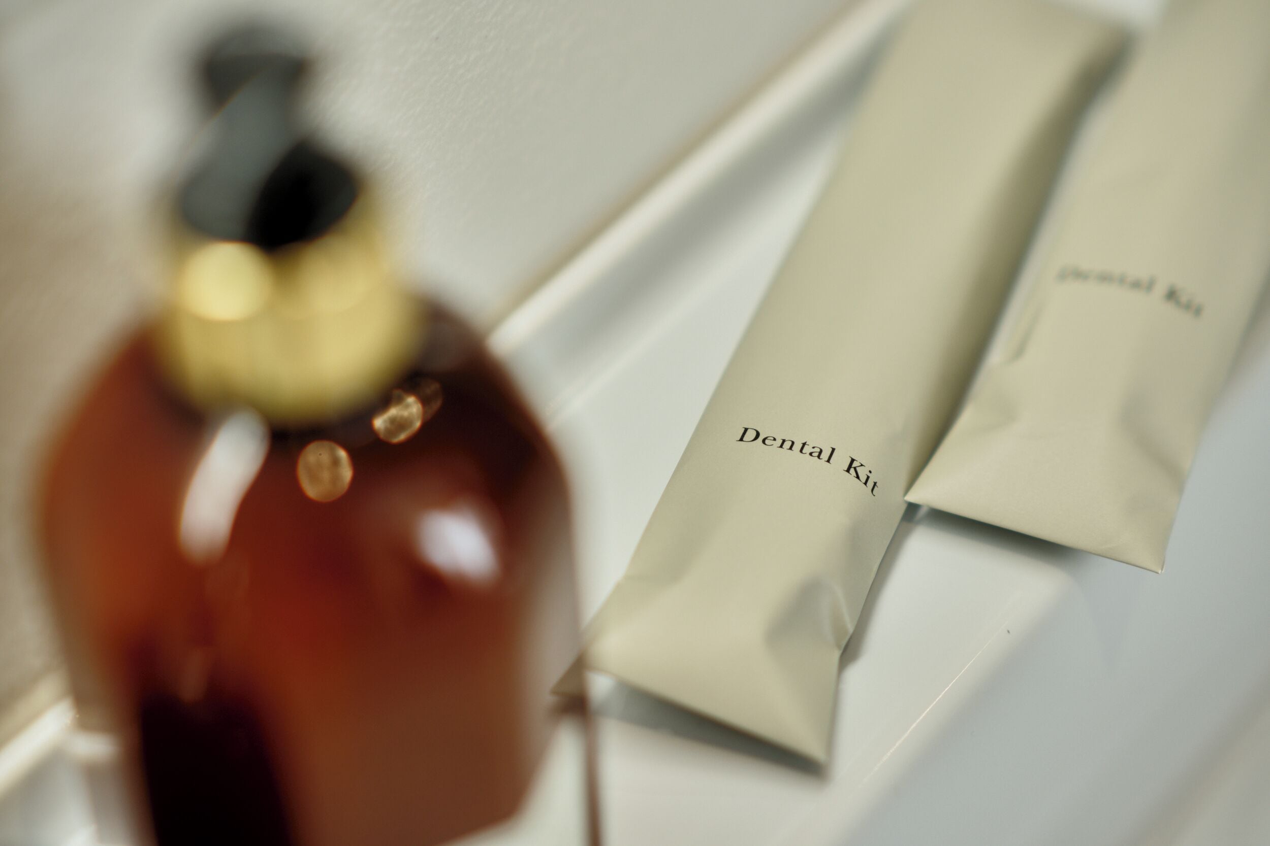 Una botella y un paquete con la etiqueta 'Dental Kit' sobre una superficie blanca.