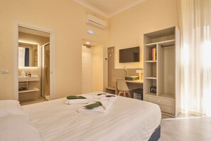 A hotel room with a bed, a desk, a TV, and a wardrobe.