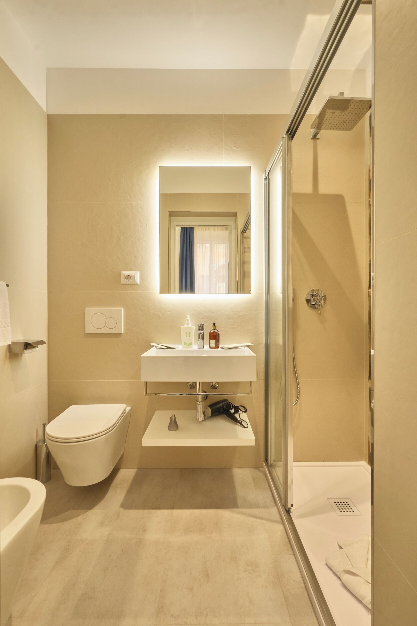 Un baño con inodoro, lavabo, espejo, ducha y un perchero para toallas.