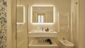 A modern bathroom with a glass shower enclosure, a white sink with a mirror above, and a bidet. - Rishon (Rome)