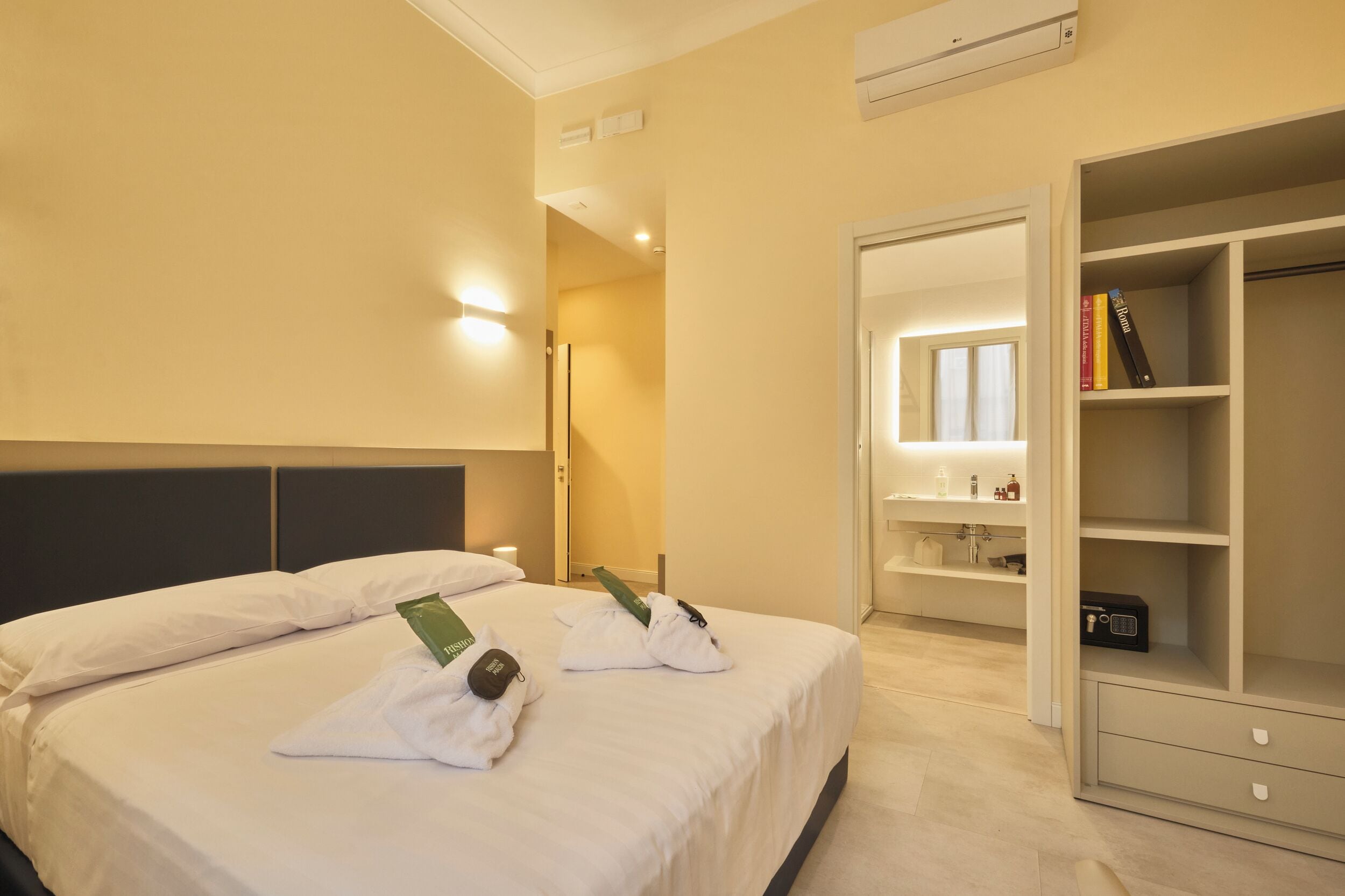 Quarto de hotel com cama bem arrumada, closet espaçoso e banheiro com espelho e prateleiras.