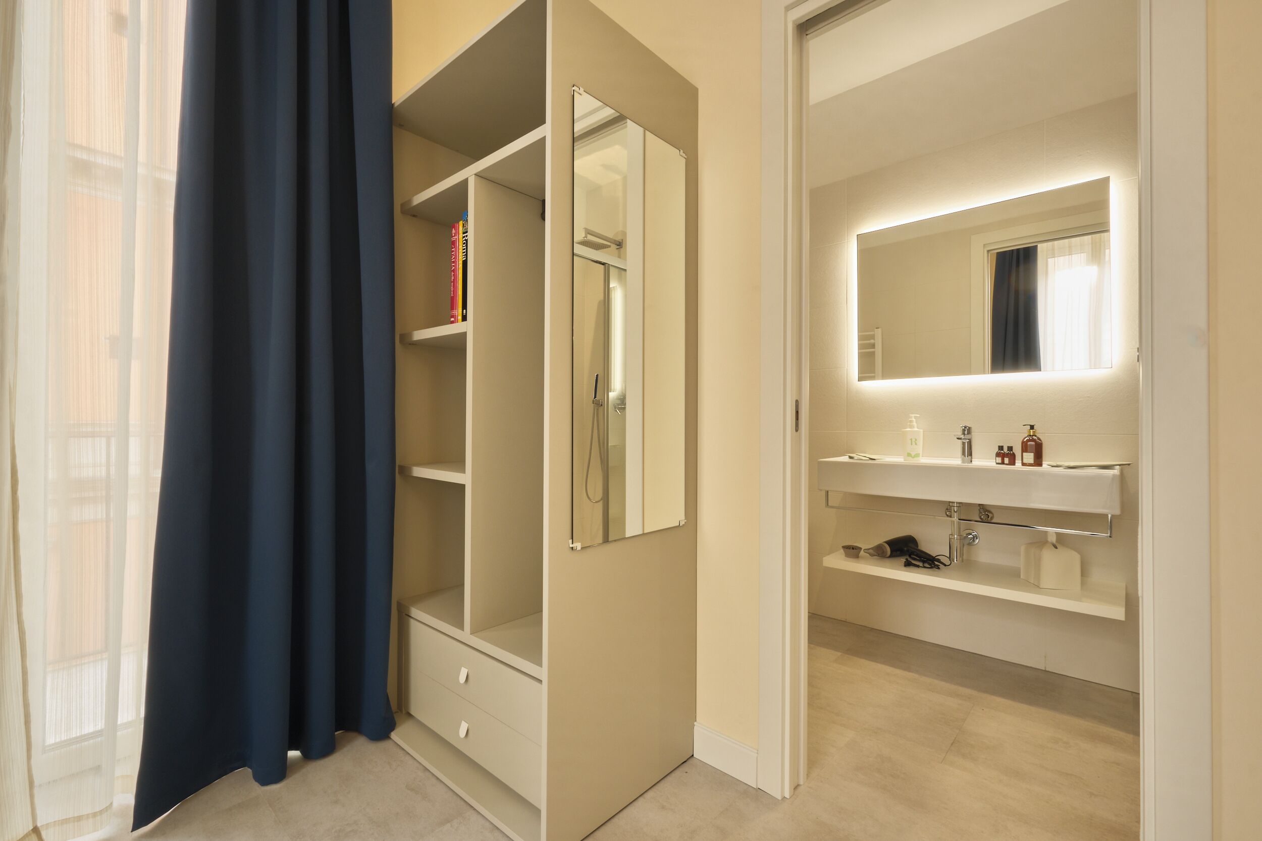 A modern bathroom with a mirror, vanity, and storage.