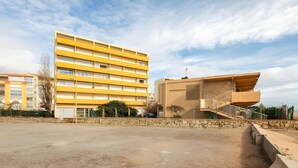 Un edificio de varios pisos con fachada amarilla, pared de piedra y una escalera que conduce a un balcón.