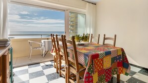 Un balcón con piso a cuadros, una mesa con colcha de colores y vista al mar.