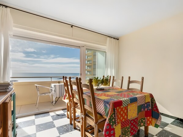 Un balcon doté d’un sol à carreaux, une table recouverte d’une courtepointe aux couleurs vives et une vue sur la mer.