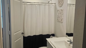 Un baño con inodoro, lavabo y cortina de ducha.