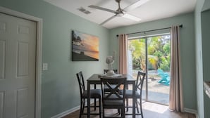 Un espace repas comprenant une table et des chaises, un ventilateur de plafond, un tableau et une vue sur l’extérieur.