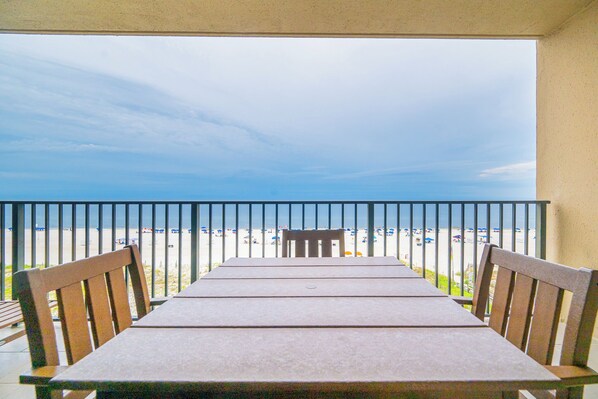 Un balcon avec une table et des chaises donnant sur une plage.