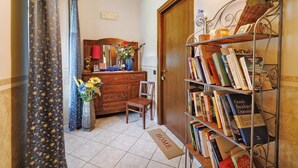 A room with a wooden dresser, a chair, a bookshelf, and a door. - Studio 'Luna' with Shared Garden, Balcony and Wi-Fi (Monforte d'Alba)
