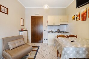 A compact kitchen with a dining table, a sofa, and a radiator. - Studio 'Luna' with Shared Garden, Balcony and Wi-Fi (Monforte d'Alba)