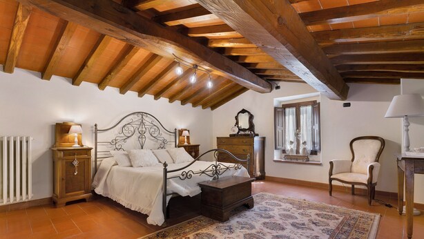 A bedroom with a wooden ceiling, a bed, a nightstand, a chair, a dresser, and a window.