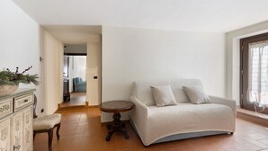 A living room with a sofa, a small round table, a cabinet, and a potted plant.