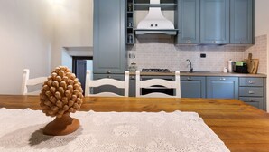 A kitchen with blue cabinets, a white stove, and a wooden dining table with a crocheted placemat.