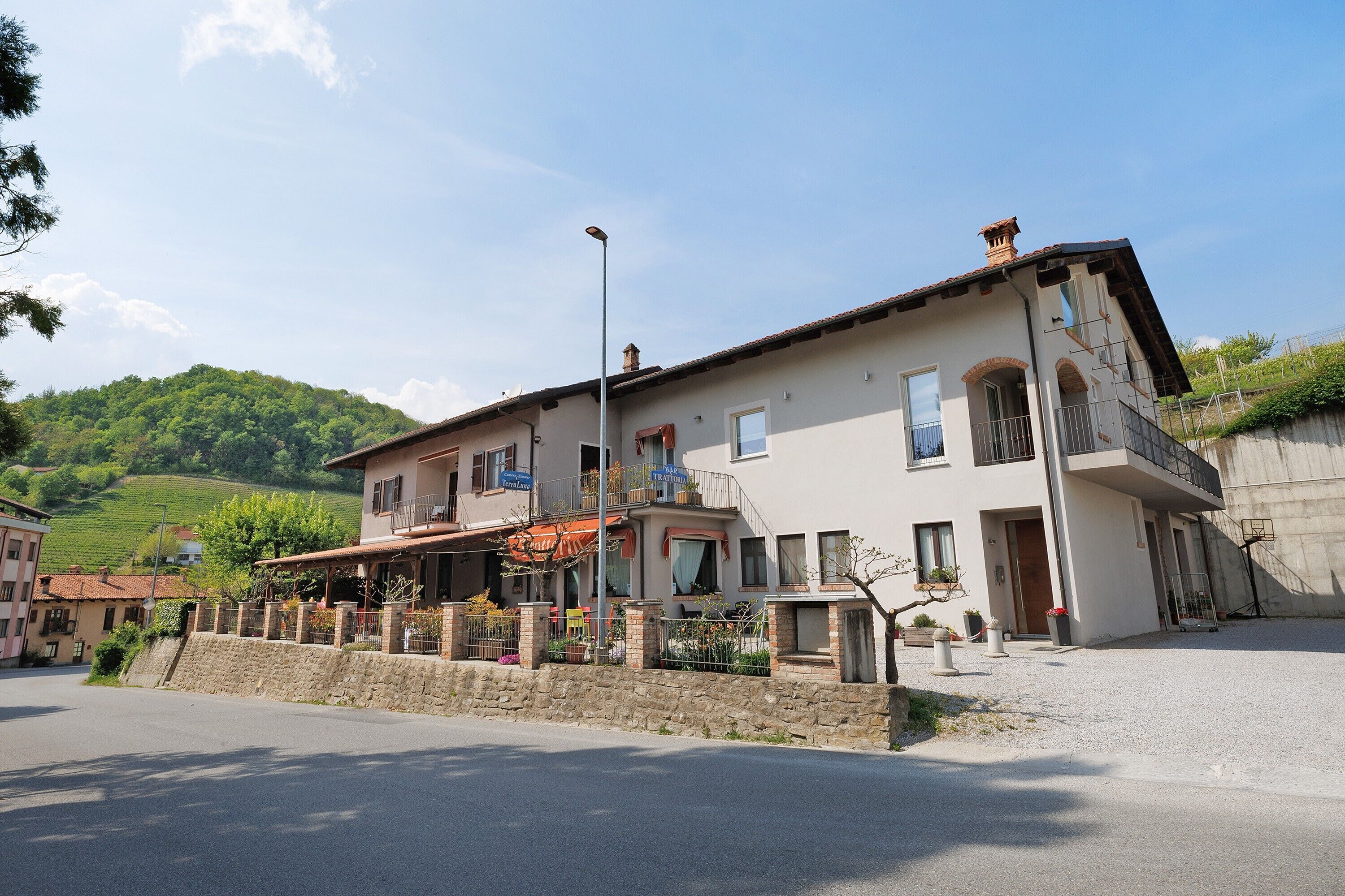 Un edificio a due piani con un balcone, un muro in pietra e una vista aperta sul paesaggio circostante.