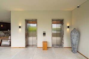 A modern lobby with two elevators, a reception desk, a wooden side table, and a large vase. - Room-serene Canggu Retreat Private Studi (Canggu)