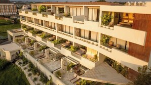 Un hôtel à plusieurs étages doté de balcons, de sièges en plein air et d’une terrasse sur le toit.