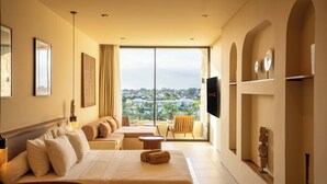 Une chambre d’hôtel avec un grand lit, un canapé, une télévision et un balcon offrant une vue sur la ville.