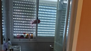 A small bathroom with a toilet, a sink, and a window with blinds. - Room-lisbon Nice & Cousy Room (Lisbon)