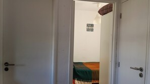 An open door leading to a room with a bed, a wall-mounted light fixture, and a small decorative item. - Room-lisbon Nice & Cousy Room (Lisbon)