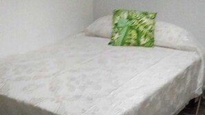 A bed with a white bedspread and a green pillow in a room with a tiled floor. - Room-lisbon Nice & Cousy Room (Lisbon)