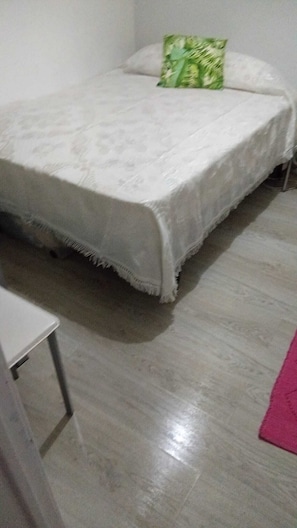 A bed with a white bedspread and a green pillow in a room with a tiled floor. - Room-lisbon Nice & Cousy Room (Lisbon)