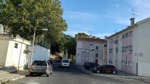 A residential street with parked cars, a pedestrian crossing, and buildings with balconies. - Room-lisbon Nice & Cousy Room (Lisbon)