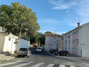 A residential street with parked cars, a pedestrian crossing, and buildings with balconies. - Room-lisbon Nice & Cousy Room (Lisbon)