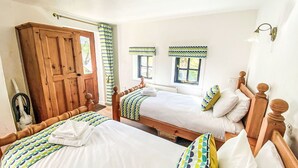 Een kamer met twee houten bedden, een houten kast en een raam met uitzicht.