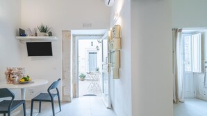 Una cucina moderna con zona pranzo, televisore e corridoio che porta al bagno.