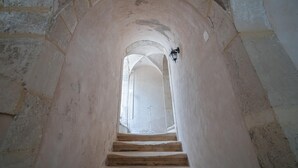 Una scala in pietra conduce a un livello superiore, con un punto luce a parete.