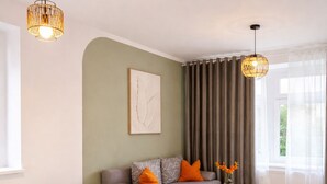 Quarto moderno com cama grande, sofá, mesinha e janela ampla com cortinas.