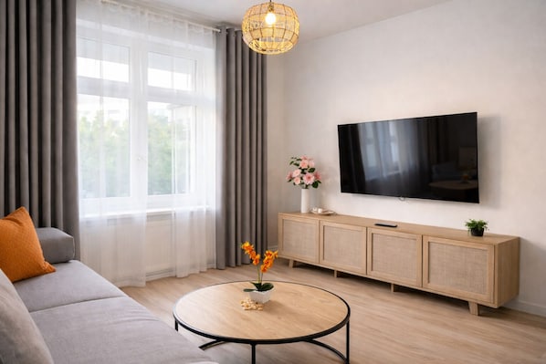 Ein modernes Wohnzimmer mit einer Couch, einem Couchtisch, einem Fernseher und einem Schrank.