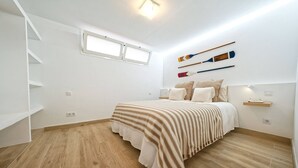 Ein Schlafzimmer mit Bett, Fenster, Wandregal und Treppe.