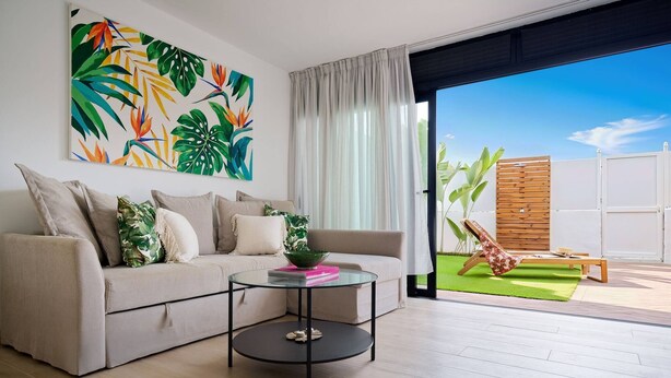 Ein modernes Wohnzimmer mit einer Couch, einem Couchtisch und einem großen Fenster.