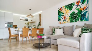 Ein modernes Wohnzimmer mit einer Couch, einem Couchtisch und einem Essbereich mit Korbstühlen.