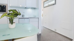 Une cuisine moderne avec des meubles blancs, un plan de travail en verre et une plante en pot.