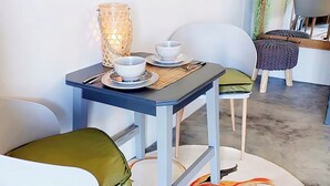 A dining area with a table set for two, chairs, a decorative rug, and a hanging plant. - Charming Garden Route Villa, Nature View and BBQ Bliss (Mossel Bay)