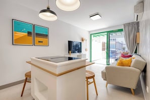 A modern living room with a kitchen island, a sofa, and artwork on the wall.
