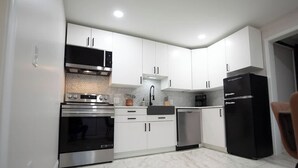 Una cocina moderna con armarios blancos, electrodomésticos de acero inoxidable y un refrigerador negro.