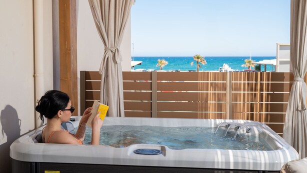 Une personne se détend dans un bain à remous, avec vue sur la plage et l’océan.