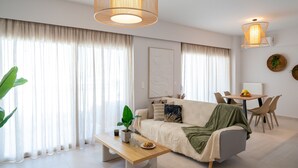 Un salon moderne avec un canapé, une table à manger et un luminaire suspendu.