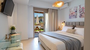 Une chambre d’hôtel moderne équipée d’un lit, d’un bureau en verre, d’une télévision et d’un balcon avec des meubles d’extérieur.