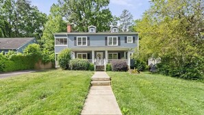 A two-story house with a front porch, a visible front yard, and a pathway leading to the entrance. - Sleeps 10 - Plaza Midwood - Walk to Restaurants (Charlotte)