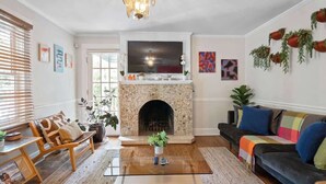 A living room with a fireplace, sofa, coffee table, and various plants. - Sleeps 10 - Plaza Midwood - Walk to Restaurants (Charlotte)