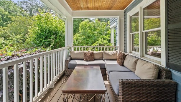A covered porch with a wooden ceiling, a cushioned seating area, and a view of greenery. - Sleeps 10 - Plaza Midwood - Walk to Restaurants (Charlotte)